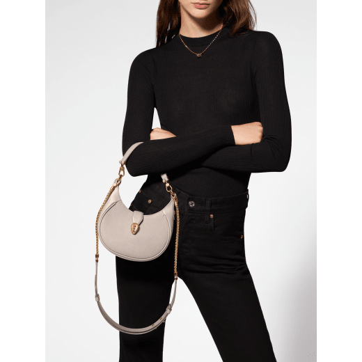Serpenti Ellipse small crossbody bag in Urban grain and smooth ivory opal calf leather with flamingo quartz pink gros grain lining. Captivating snakehead closure in gold-plated brass embellished with black onyx scales and red enamel eyes. 1204-UCL image 8
