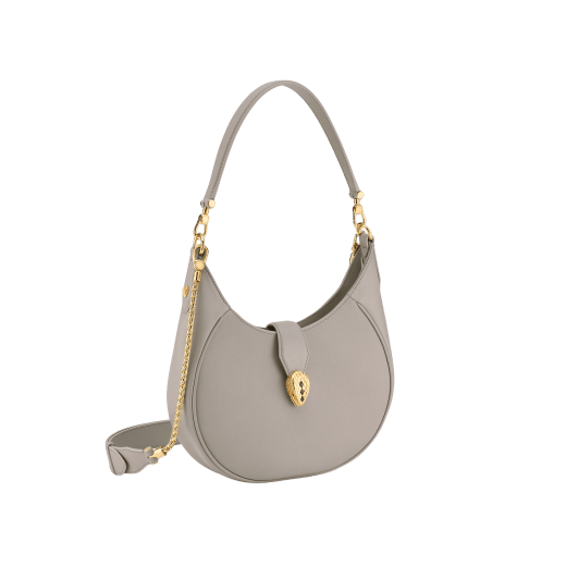 Serpenti Ellipse medium shoulder bag in Urban grain and smooth Niagara sapphire blue calf leather with cloud topaz blue gros grain lining. Captivating snakehead closure in gold-plated brass embellished with black onyx scales and red enamel eyes. 1190-UCL image 2