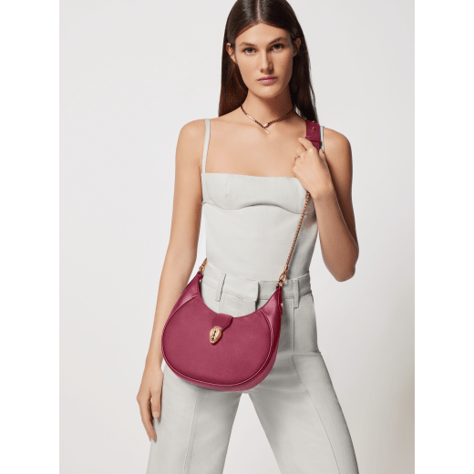 Serpenti Ellipse medium shoulder bag in Urban grain and smooth ivory opal calf leather with flamingo quartz pink gros grain lining. Captivating snakehead closure in gold-plated brass embellished with black onyx scales and red enamel eyes. 1190-UCL image 7