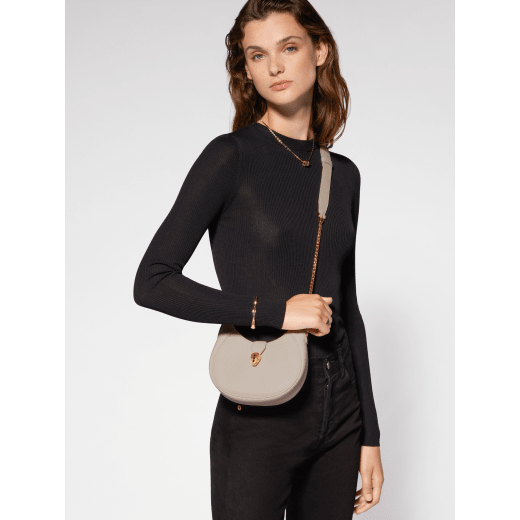 Serpenti Ellipse small crossbody bag in Urban grain and smooth ivory opal calf leather with flamingo quartz pink gros grain lining. Captivating snakehead closure in gold-plated brass embellished with black onyx scales and red enamel eyes. 1204-UCLa image 1