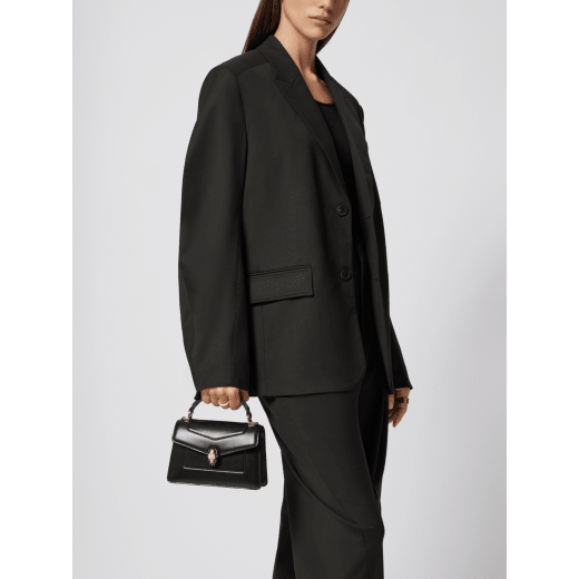 Serpenti Forever mini top handle bag in black calf leather with black nappa leather lining. Captivating snakehead magnetic closure in light gold-plated brass embellished with black enamel and light gold-plated brass scales, and black onyx eyes. SEA-1283-CL image 1