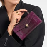 Serpenti Forever phone case in Smeraldo Prezioso shiny karung with black nappa leather lining. Captivating snakehead magnetic closure in gold-plated brass embellished with gold-plated and black enamel scales, and black onyx eyes. SEA-PHONEPOUCH-Kar image 1