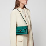 Serpenti Forever East-West small shoulder bag in black calf leather with emerald green grosgrain lining. Captivating snakehead magnetic closure in light gold-plated brass embellished with black and white agate enamel scales, and green malachite eyes. 1237-CL image 7