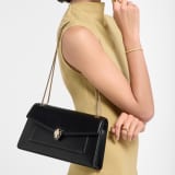 Serpenti Forever medium shoulder bag in black calf leather with black nappa leather lining. Captivating snakehead magnetic closure in light gold-plated brass embellished with beige noisette enamel and light gold-plated brass scales, and black onyx eyes. SEA-001-1344M image 1
