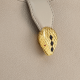 Serpenti Ellipse small crossbody bag in Urban grain and smooth ivory opal calf leather with flamingo quartz pink gros grain lining. Captivating snakehead closure in gold-plated brass embellished with black onyx scales and red enamel eyes. 1204-UCL image 6