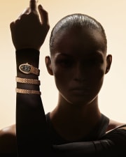 Model in the shadow wearing a Serpenti Spiga rose gold double-coil watch with black dial and diamonds.