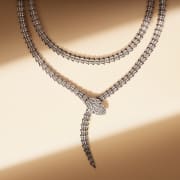Serpenti High Jewellery double coil necklace in white gold with diamonds, light and shadow background.