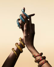 Serpenti Heritage secret watches with colourful enamels wrapping around the model's wrists, close up.