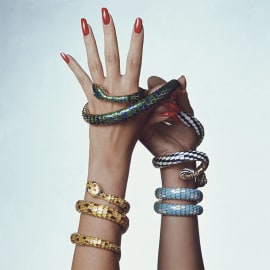Model's wrists wrapped in multiple Serpenti Heritage secret watches with colourful enamels, close up.