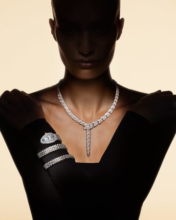 Model in the shadow wearing a white gold Serpenti necklace and Serpenti Spiga watch both with diamonds.