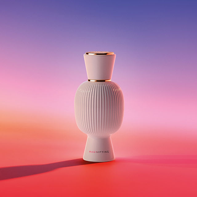 The all-white bottle of the Bvlgari Allegra Magnifying Essence, creative shot with colourful background.