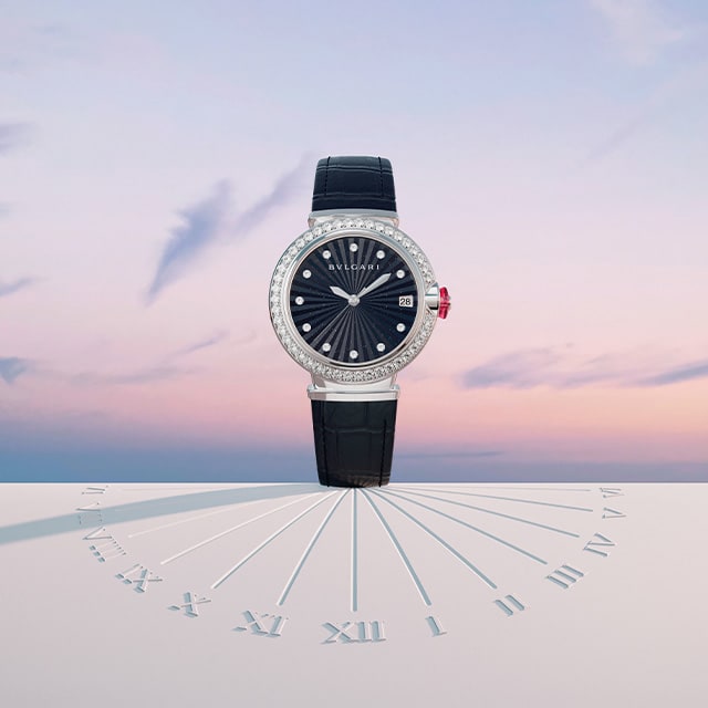 LVCEA Intarsio Uhren mit Gehäuse aus Stahl, eine mit Diamanten, Zifferblatt mit grauer Perlmutt-Intarsie und Armband aus schwarzem Alligatorleder vor einem weißen Hintergrund mit Bvlgari Logo.