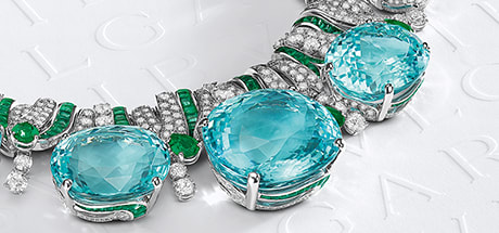 High Jewelry necklace with five Paraiba tourmalines, emeralds and diamonds, Bulgari logo backdrop.