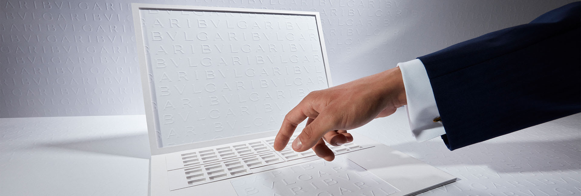 Hand over a laptop with white Bulgari logo backdrop to represent the Click & Collect service.