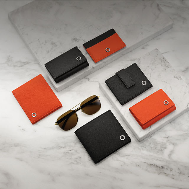 Carteiras, porta-chaves e porta-cartões de crédito Bvlgari Bvlgari em couro de novilho preto e laranja e óculos de sol Bvlgari masculinos com lentes marrons.