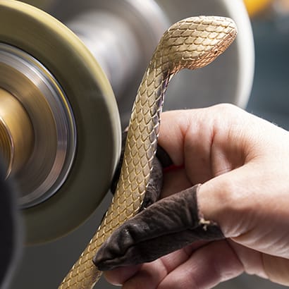 Artisan polishing the snake body shaped metallic frame of the Bulgari Serpentine pouch, close up.