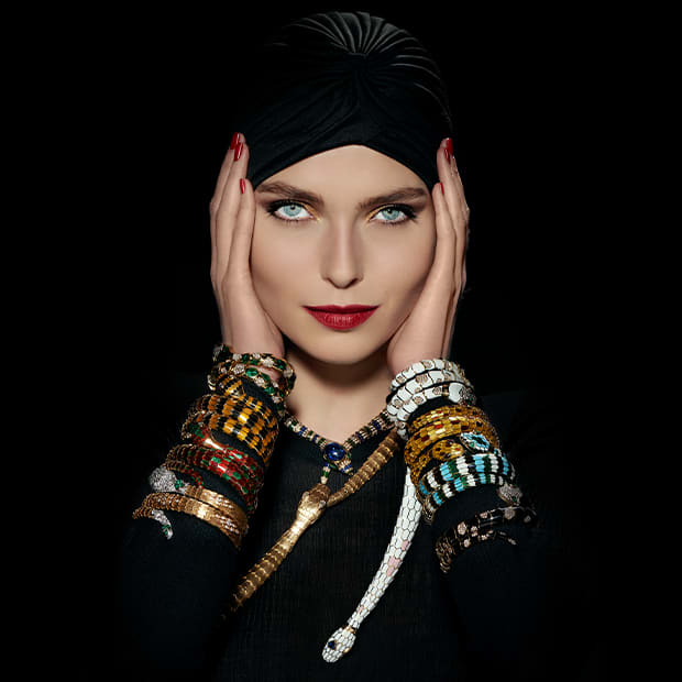 Models of different eras wearing Serpenti jewelry and the Bulgari B wrapped in Serpenti creations.