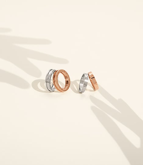 B.zero1 and BULGARI BULGARI couple rings in white and rose gold, white backdrop with shadow of hands.