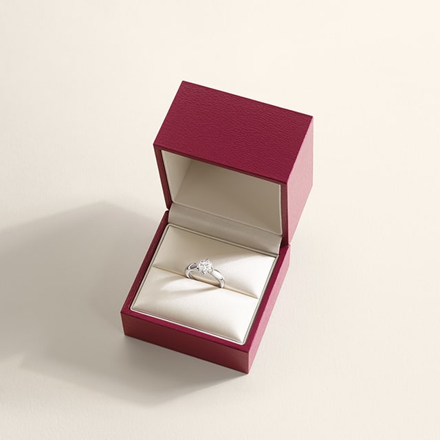 Bulgari Torcello engagement ring in platinum with a brilliant-cut diamond inside an open red box.