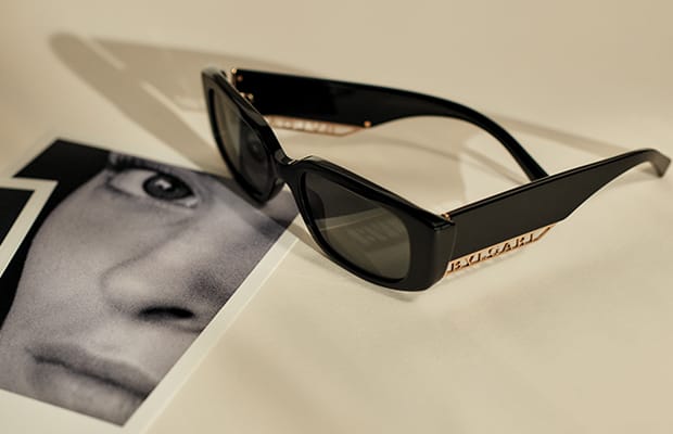 نظارة شمسية «بي.زيرو1 داونتاون» من الأسيتات الأسود عليها شعار بولغري المعدني، تستند إلى صورة.