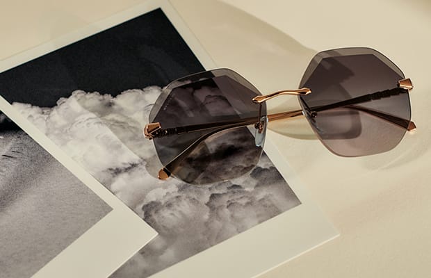Serpenti Viper frameless sunglasses with hexagonal lenses resting on a photo.