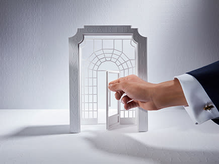 يدّ تفتح مجسماً مصغراً لبوابة متجر بولغري على خلفية بيضاء للإشارة إلى خدمة حجز المواعيد.