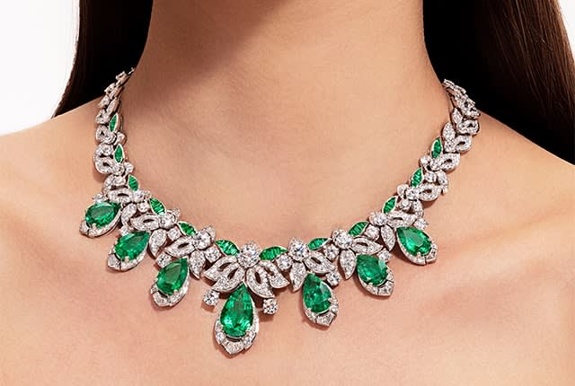 Model wearing the Acanthus Emerald Mediterranea High Jewelry platinum necklace with emeralds and diamonds. Close-up.