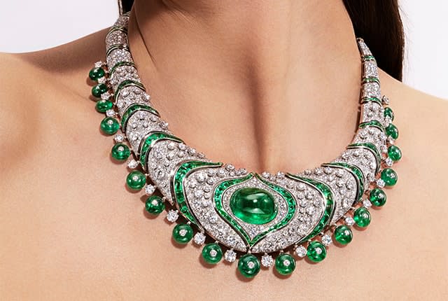 Model wearing Emerald Lotus High Jewelry platinum necklace with emeralds and diamonds, close-up.