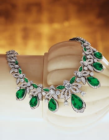 Model wearing Acanthus Emerald Mediterranea High Jewelry platinum necklace with emeralds and diamonds.