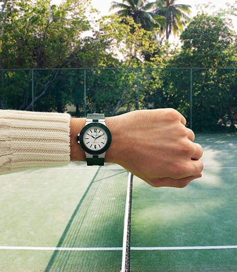 Arm with Bulgari Aluminium Match Point watch in green rubber and aluminium, at the tennis court.