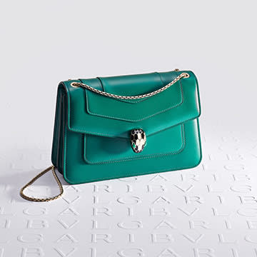 Serpenti Forever shoulder bag in green calf leather with snakehead closure, white Bulgari logo backdrop.