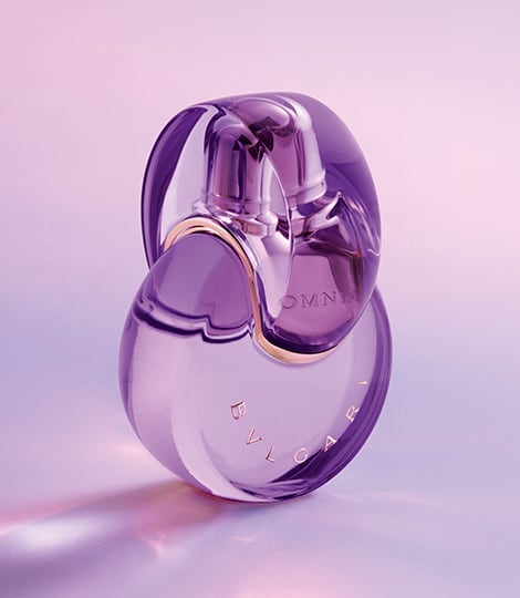 Purple Omnia Amethyste fragrance bottle in the infinity shape, purple backdrop, close-up.
