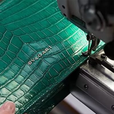 Sewing of a green crocodile panel during the making of a Bulgari handbag.