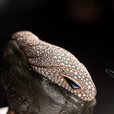 Bulgari Serpenti heritage jewellery creation, close up on the rose gold head with diamonds and onyx eyes.