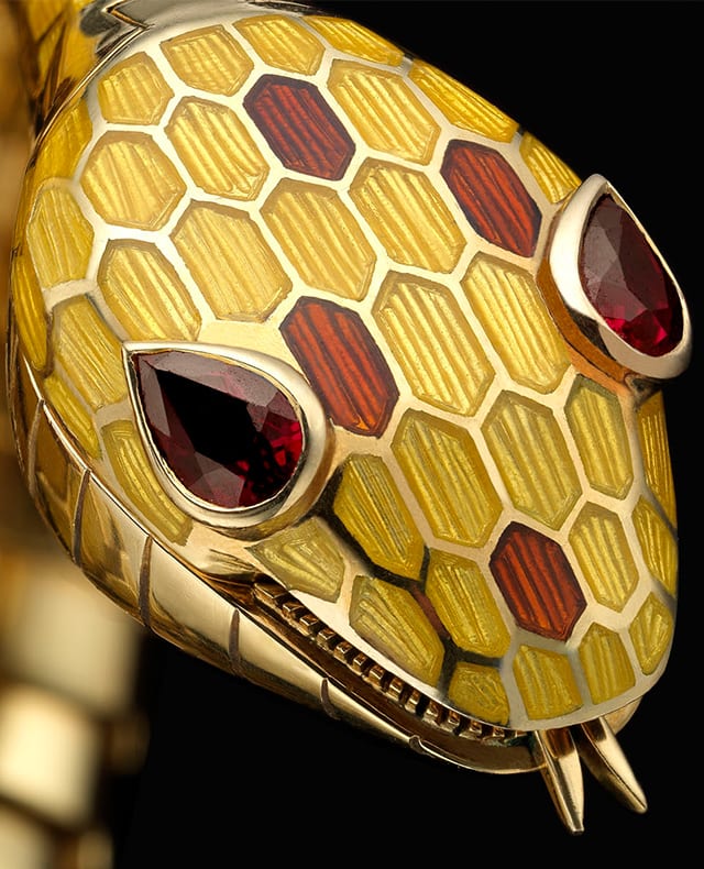 Bulgari Heritage Serpenti secret watch with yellow and brown enamel scales and ruby eyes, close up.