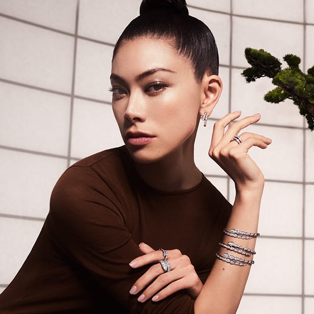 Hikari Mori from the side wearing white gold Serpenti Viper bangles, rings and earrings with diamonds.