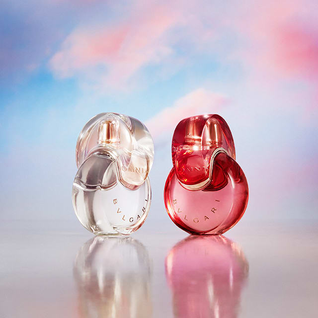 Omnia Crystalline, Omnia Amethyste and Omnia Coral fragrance bottles against a white, purple and red background.