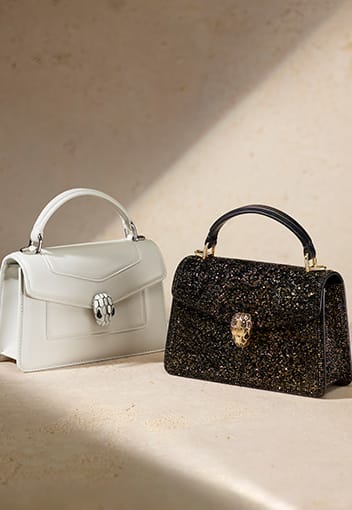 Serpenti Top Handle Mini bags in white calf leather and black Crystal Sparkle, neutral background.
