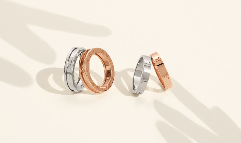 B.zero1 and BULGARI BULGARI couple rings in white and rose gold, white backdrop with shadow of hands.