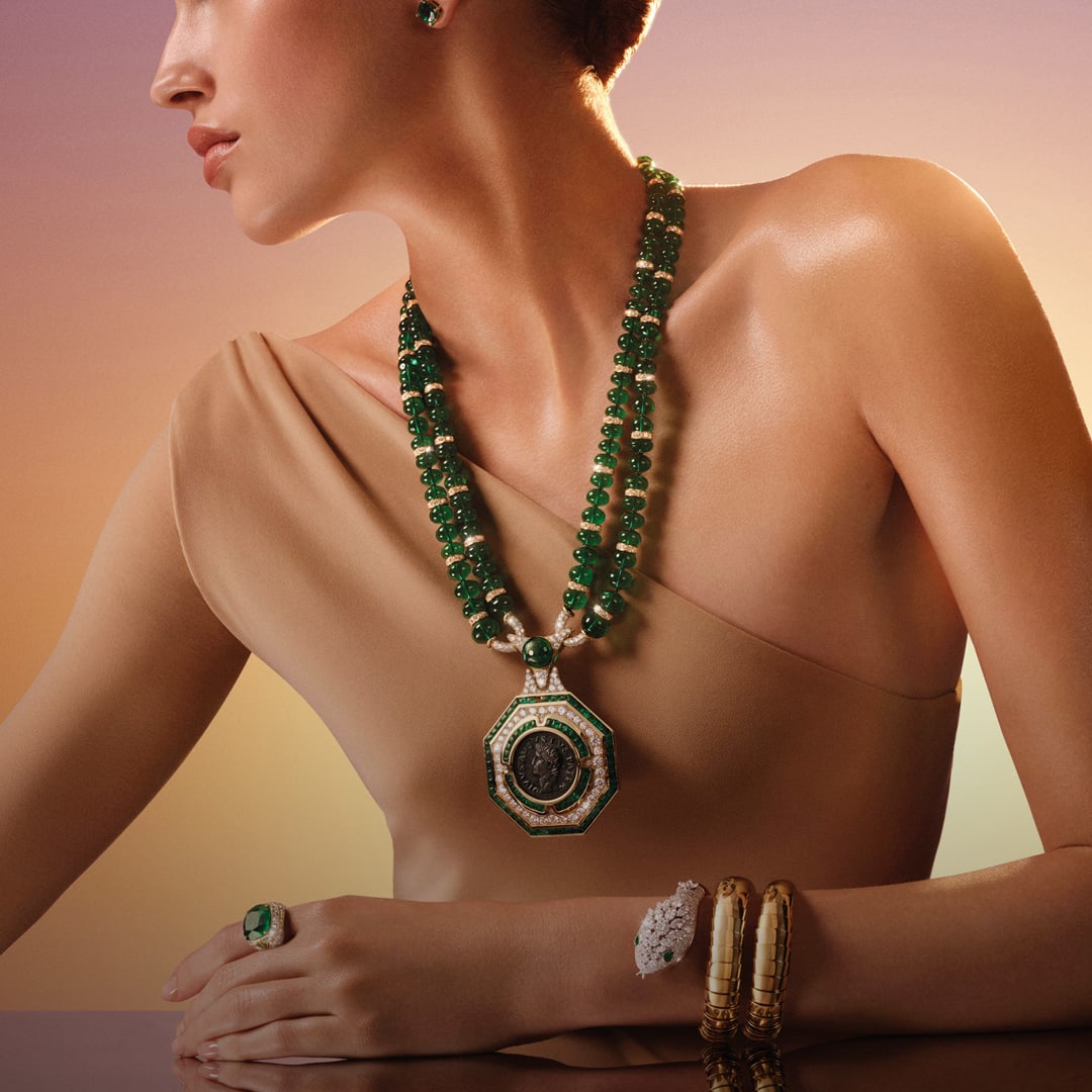 模特兒配戴 Aeterna High Jewellery 系列的長項鍊、手環和戒指，背景為黎明時分的天空。