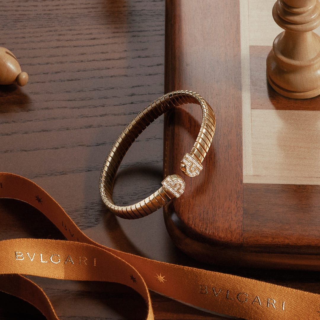 Yellow gold Bvlgari Tubogas bracelet on chessboard corner with orange ribbon.
