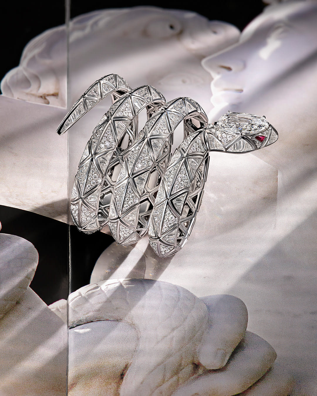 Serpenti Infinia High Jewellery double-spiral white gold bracelet with diamonds and ruby eyes.