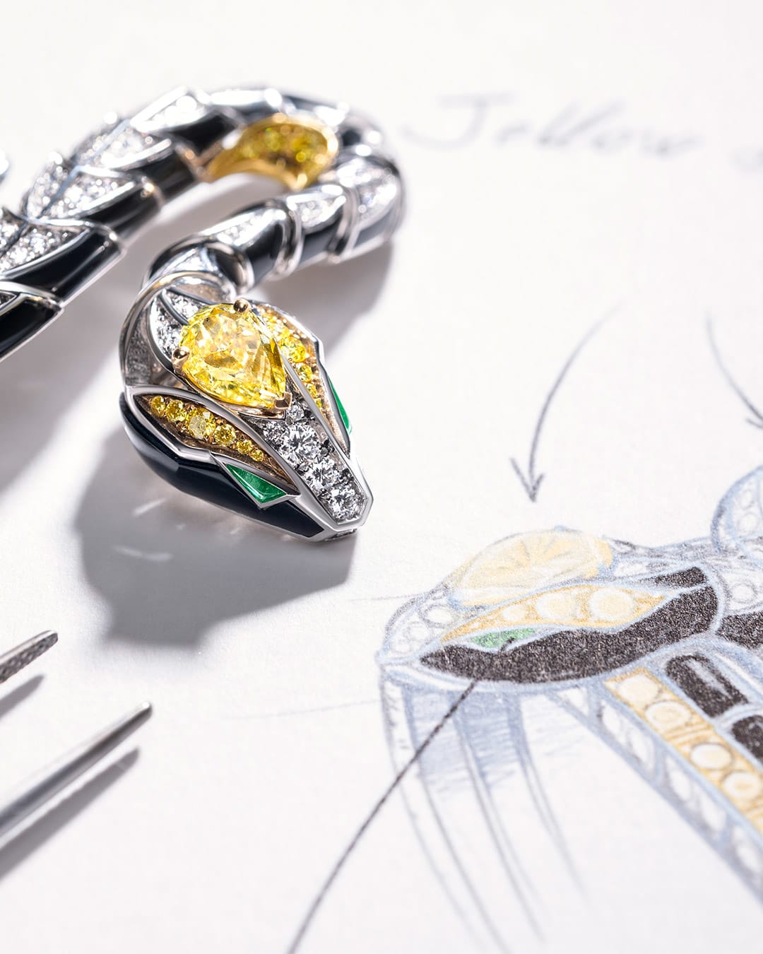 Detail of Serpenti Spira High Jewellery white gold cuff with yellow diamonds and onyx, sketch behind.