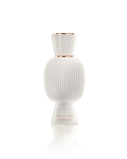 White flacon of the Bvlgari Allegra Magnifying Vanilla essence in front of vanilla beans, creative shot.
