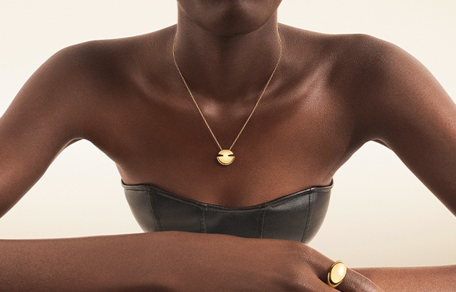 Model wearing Bulgari Cabochon 18 kt yellow gold rings and pendant necklace, close up.