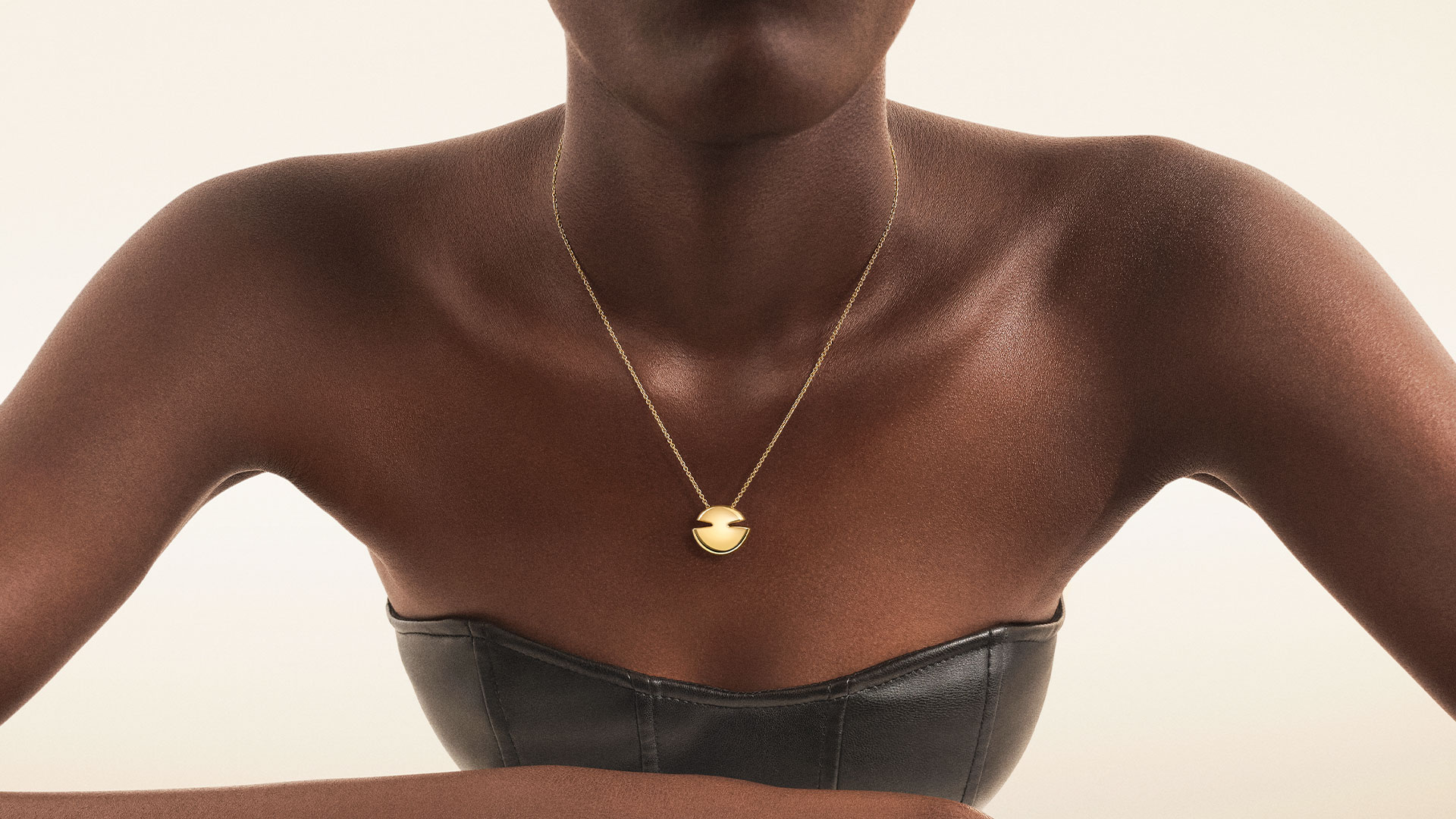 Model wearing Bulgari Cabochon 18 kt yellow gold rings and pendant necklace, close up.