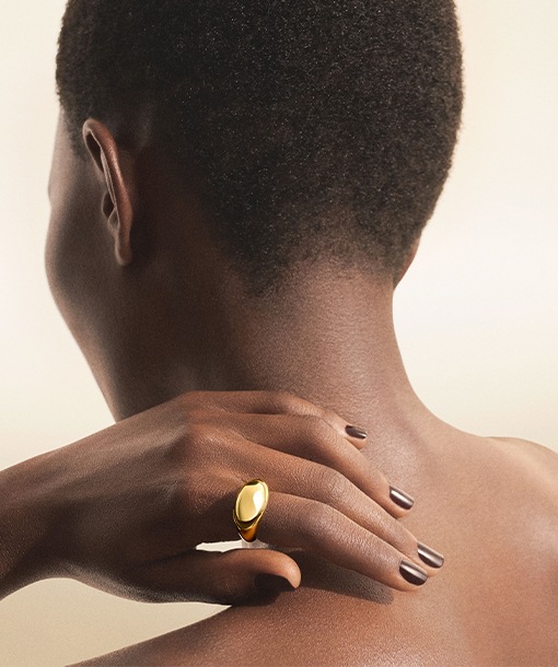 Model from the back wearing a Bulgari Cabochon ring in 18 kt yellow gold, close up.